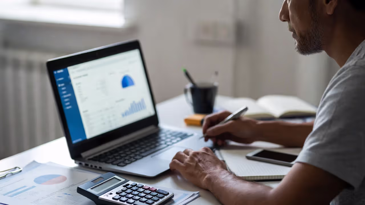 Small business owner reviewing HRMS data and payroll information on a laptop